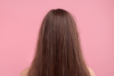 Woman with damaged messy hair on pink background, back view