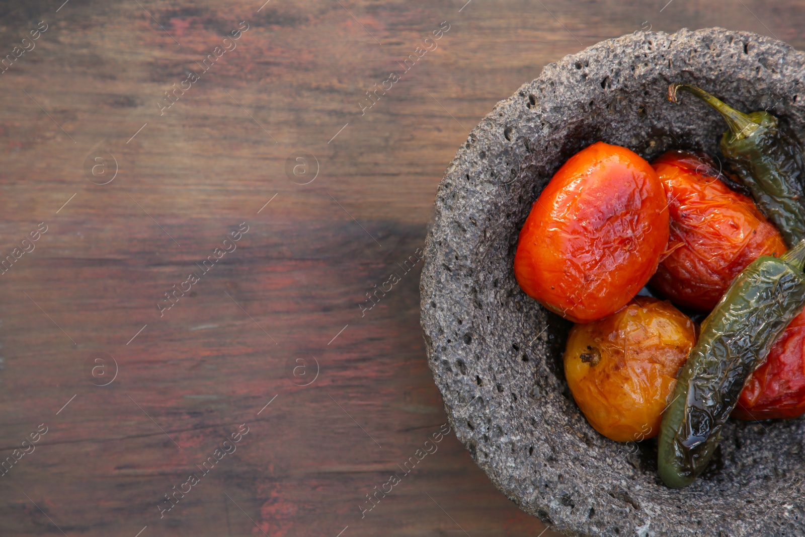 Photo of Ingredients for salsa sauce in stone bowl on wooden table, top view. Space for text