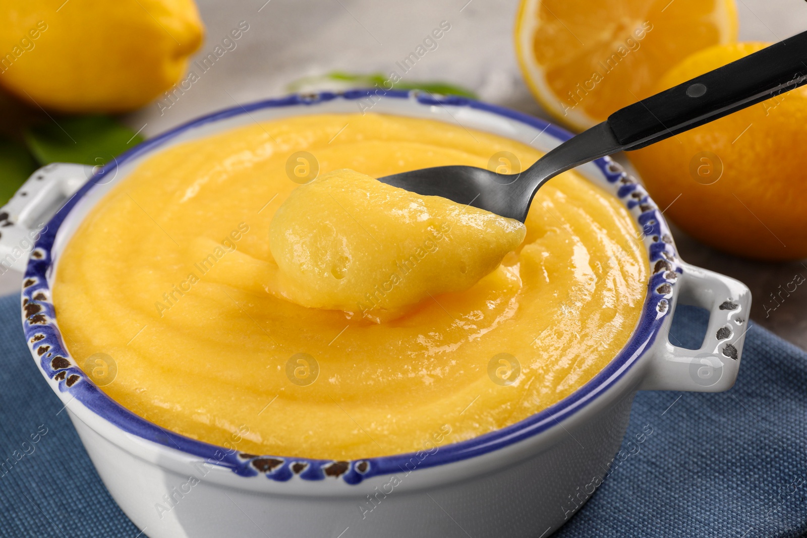 Photo of Taking delicious lemon curd from bowl at table, closeup