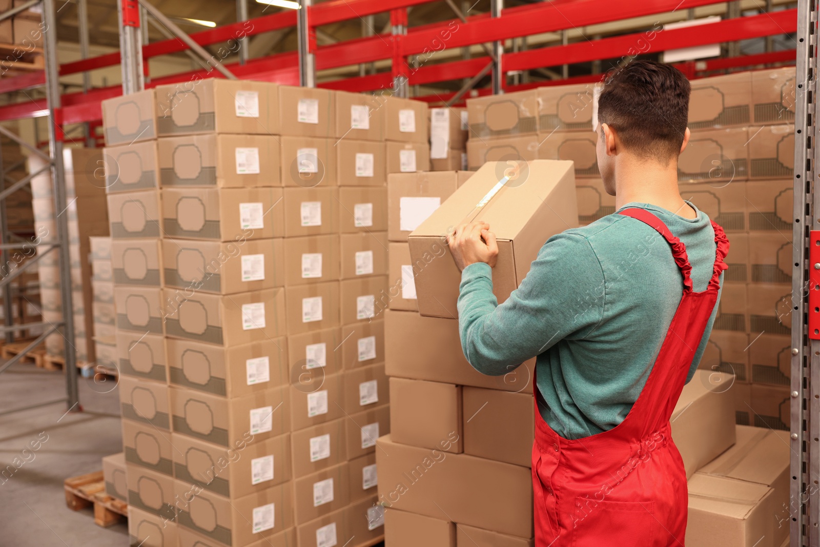 Photo of Worker stacking cardboard boxes in warehouse. Wholesaling