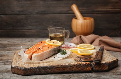 Photo of Fresh raw salmon steak with seasonings on wooden board