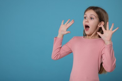 Photo of Portrait of surprised girl on light blue background. Space for text