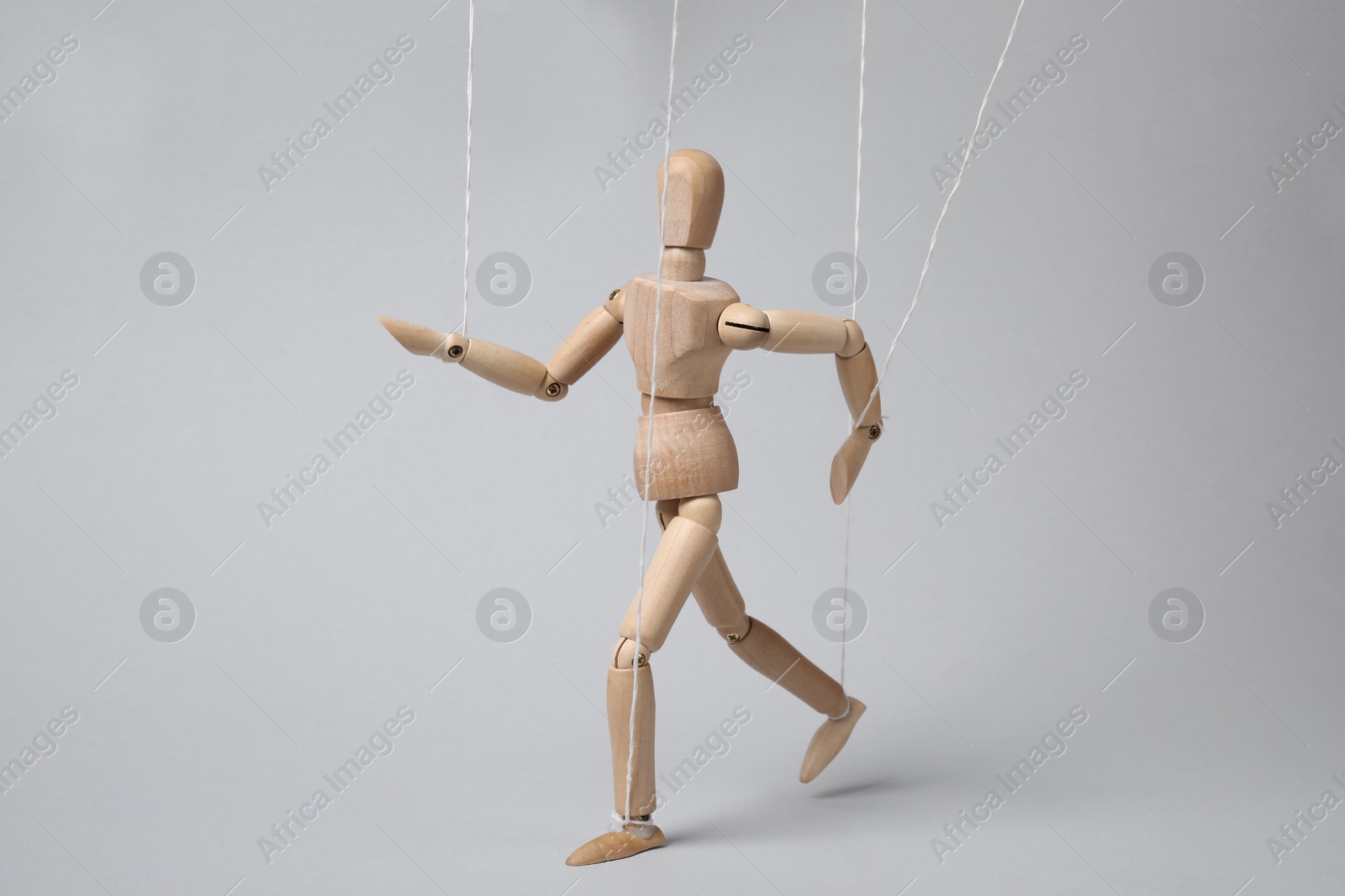 Photo of One wooden puppet with strings on light grey background