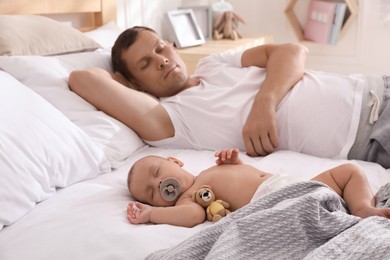 Photo of Father with his cute baby sleeping in bed at home