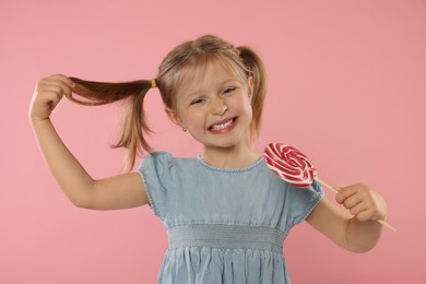 Portrait of happy girl with lollipop on pink background