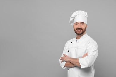 Smiling mature chef on grey background, space for text