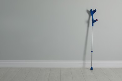 Elbow crutch near light grey wall. Space for text