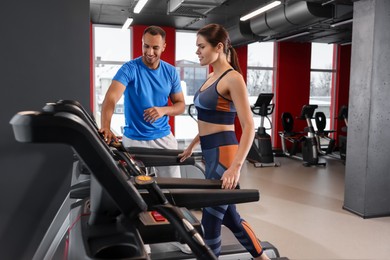 Happy trainer explaining woman how to do exercise properly in modern gym