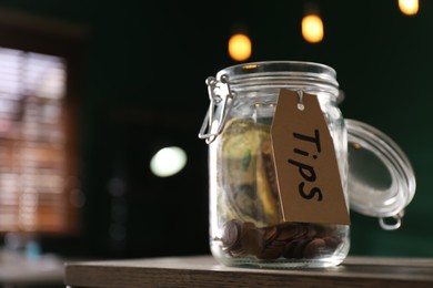 Glass jar with tips on wooden table indoors, closeup. Space for text