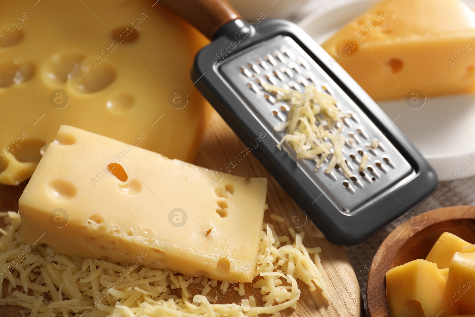 Photo of Grated, cut cheese and grater on table, closeup