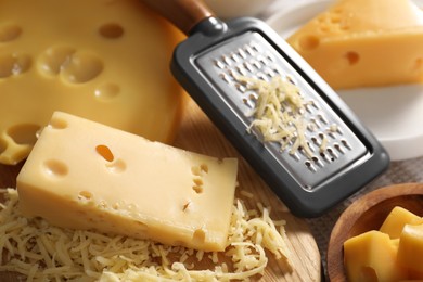 Photo of Grated, cut cheese and grater on table, closeup