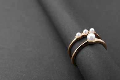 Photo of Elegant pearl rings on black background, closeup. Space for text