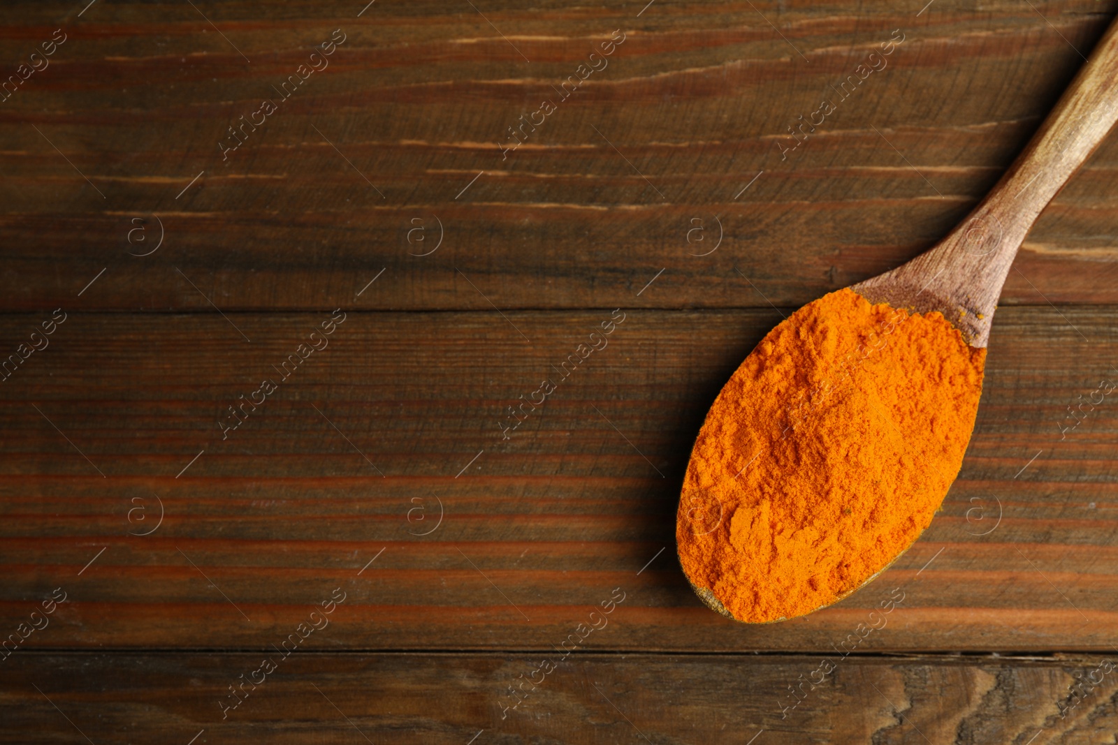 Photo of Spoon with saffron powder on wooden table, top view. Space for text