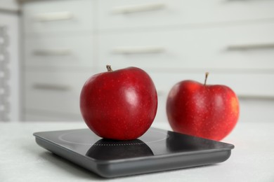 Photo of Red apples and modern digital scale on table
