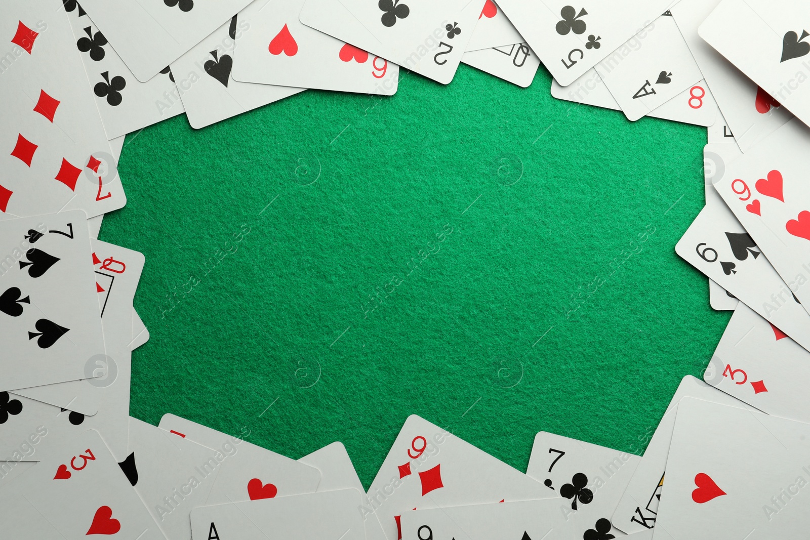 Photo of Frame made of playing cards on green table, top view. Space for text