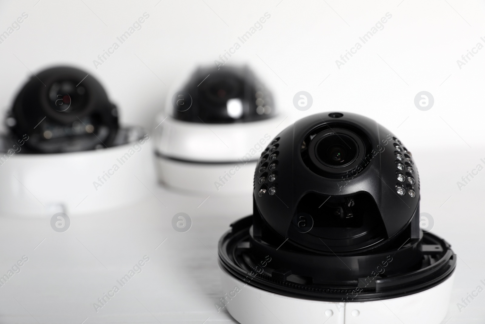 Photo of Modern CCTV cameras on table against light background. Home alarm system