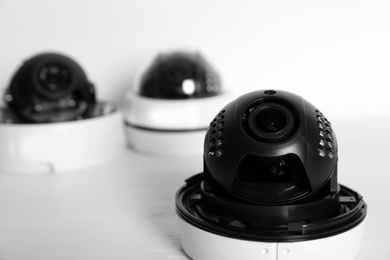 Photo of Modern CCTV cameras on table against light background. Home alarm system