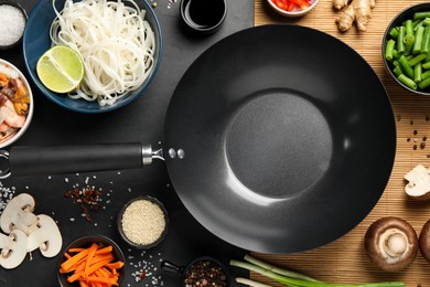 Photo of Flat lay composition with black wok surrounded by spices and products on dark table