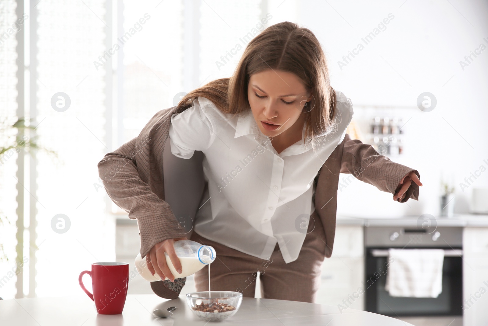 Photo of Young woman cooking breakfast in hurry at home. Morning preparations