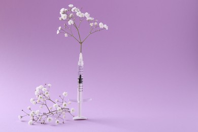 Photo of Cosmetology. Medical syringe and gypsophila on violet background, space for text