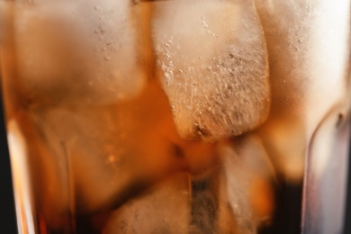 Photo of Glass of tasty refreshing cola with ice cubes, closeup