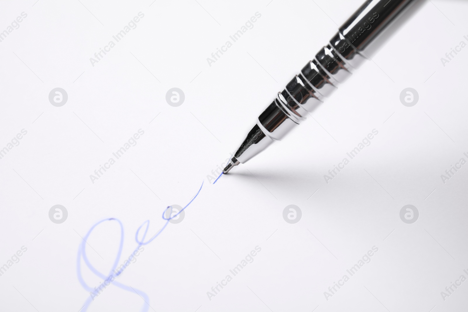 Photo of Signing on sheet of white paper with pen, closeup