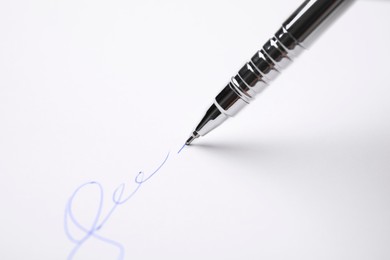 Signing on sheet of white paper with pen, closeup