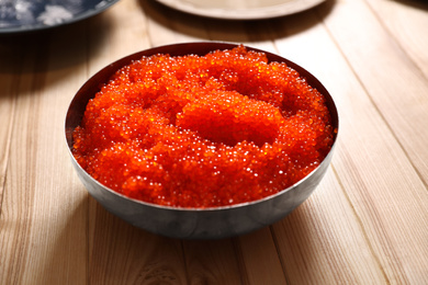 Photo of Fresh red caviar in bowl on wooden table
