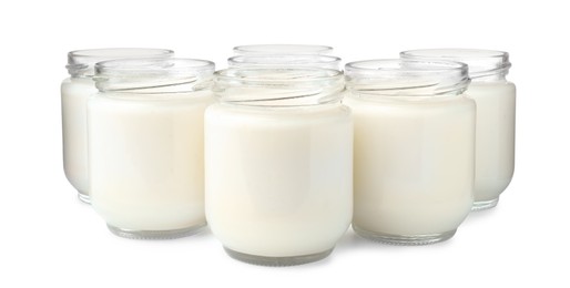 Glass jars with delicious homemade yogurt on white background