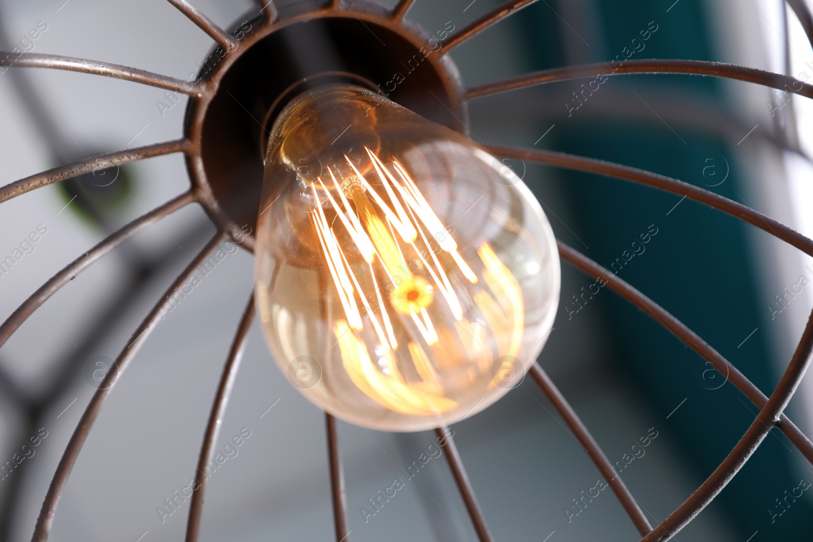 Photo of Stylish metallic pendant lamp with Edison light bulb indoors, closeup