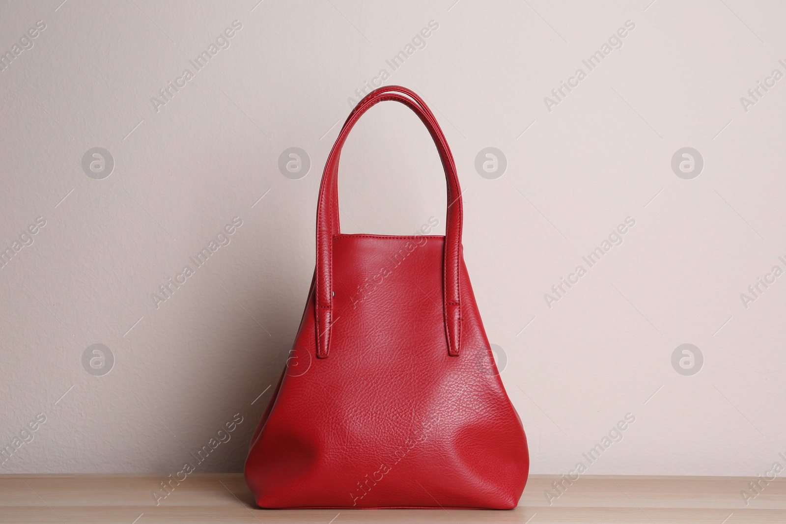 Photo of Stylish red woman's bag on wooden table