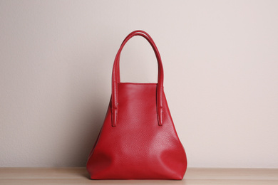 Stylish red woman's bag on wooden table