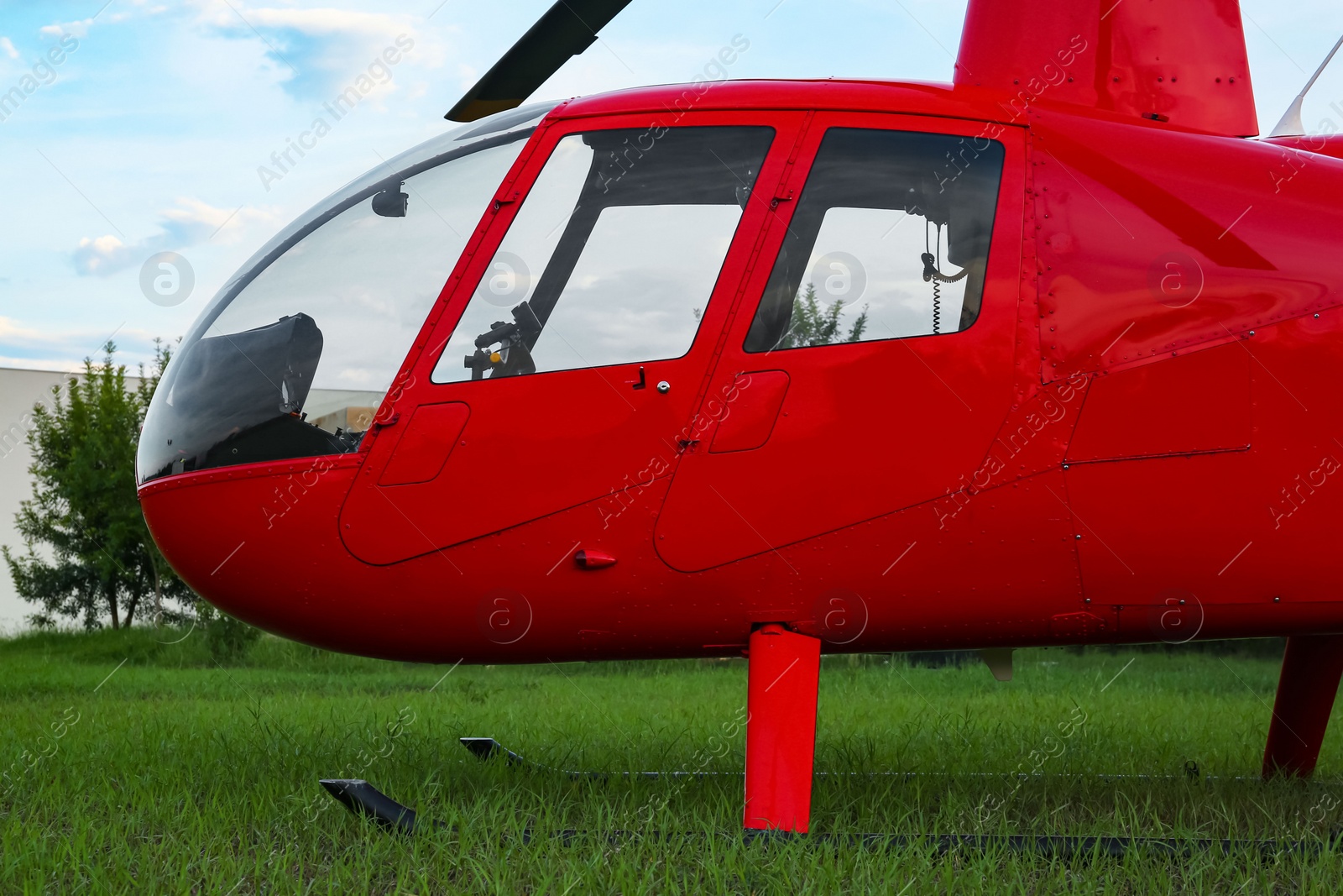 Photo of Modern red helicopter on green grass outdoors