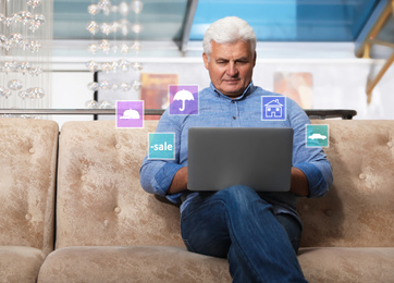 Image of Senior man using laptop on sofa in restaurant. Online shopping