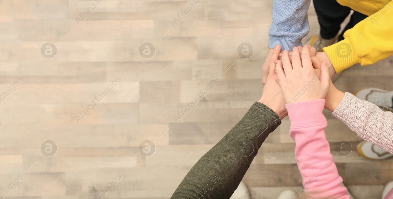 Photo of Group of people holding their hands together indoors, top view. Space for text