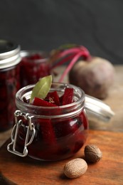 Photo of Jar with delicious pickled beets on wooden board
