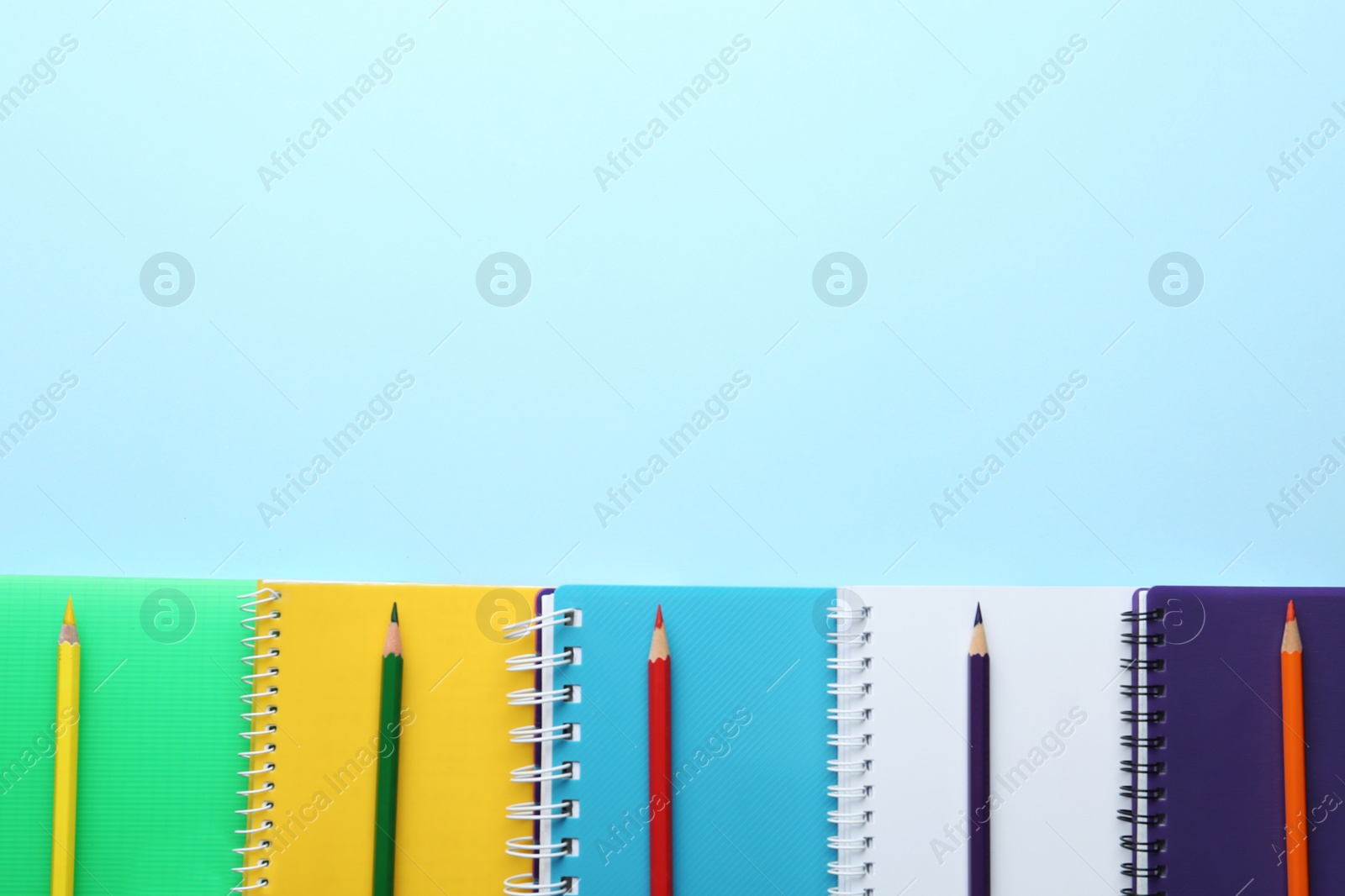 Photo of Stylish notebooks and pencils on light blue background, flat lay. Space for text