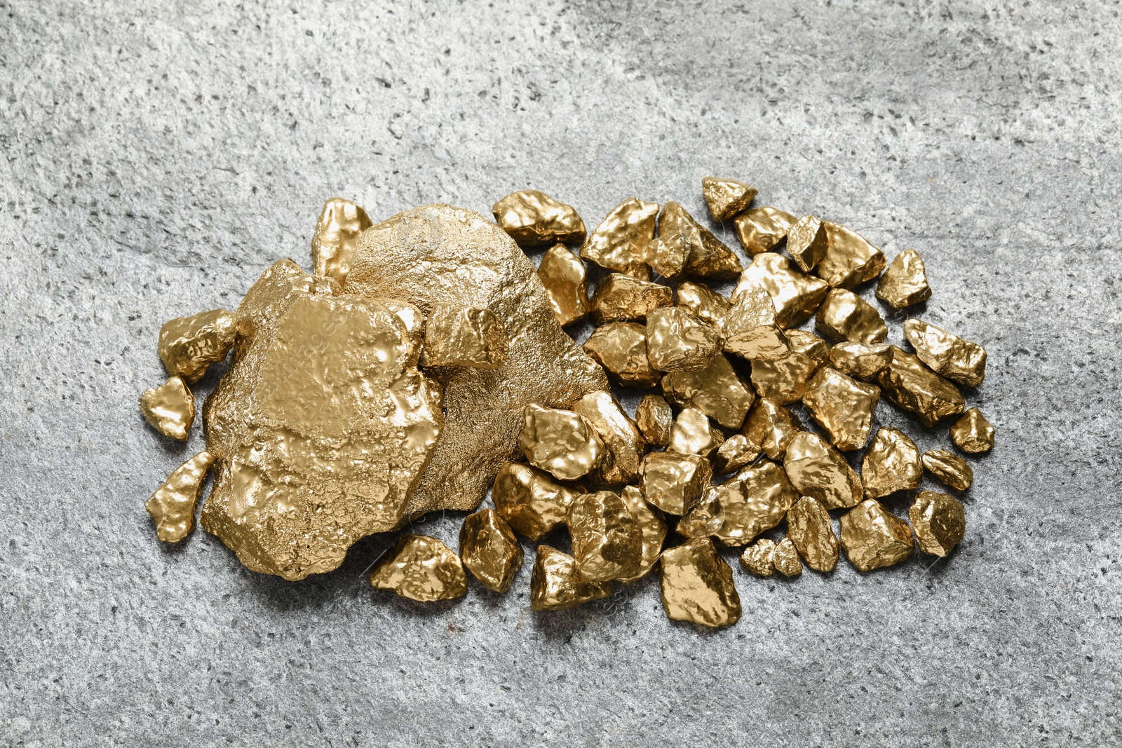 Photo of Pile of shiny gold nuggets on grey table, flat lay