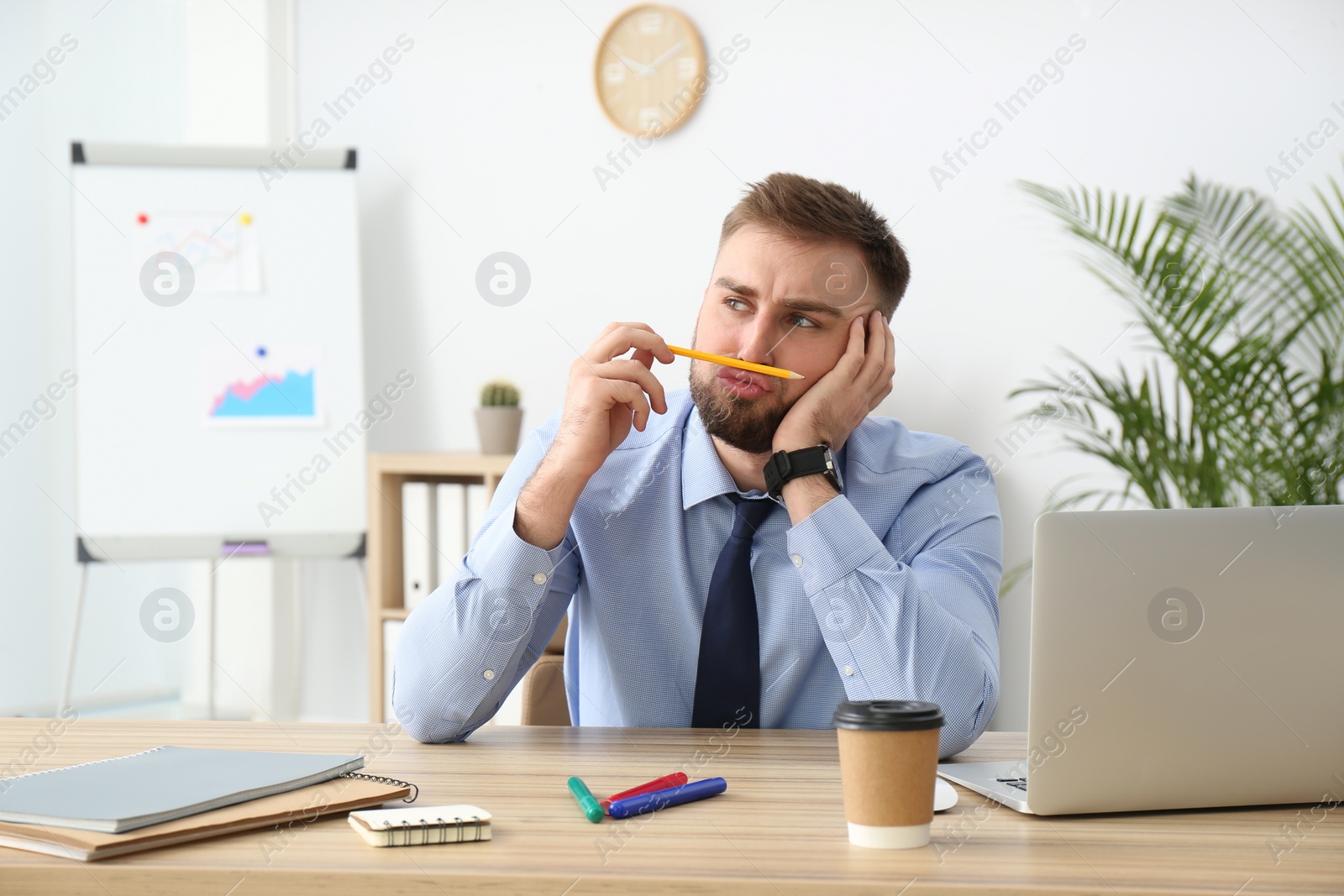 Photo of Lazy young office employee procrastinating at workplace