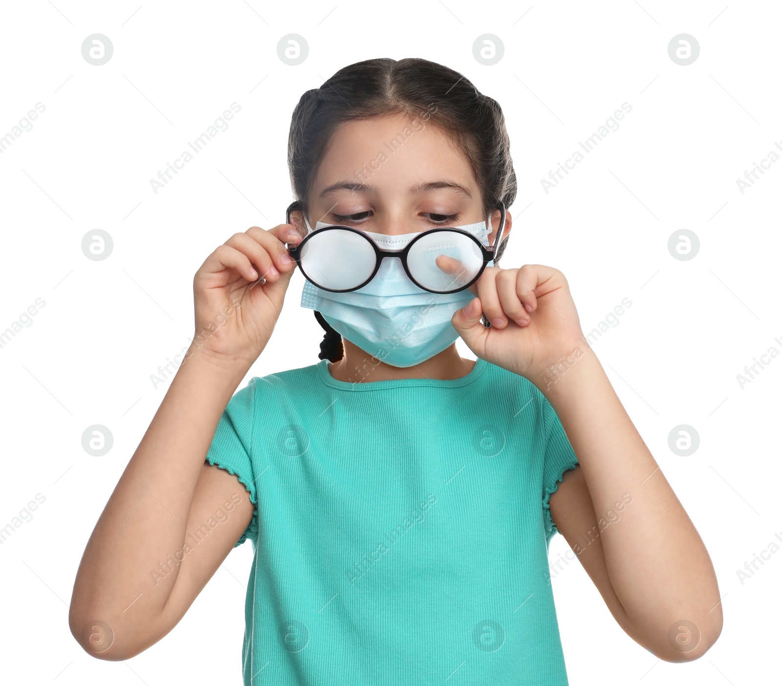 Photo of Little girl wiping foggy glasses caused by wearing medical face mask on white background. Protective measure during coronavirus pandemic