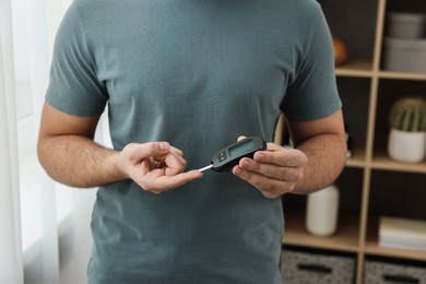 Photo of Diabetes test. Man checking blood sugar level with glucometer at home, closeup