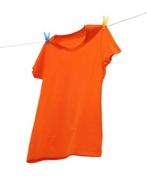 Photo of One orange t-shirt drying on washing line isolated on white