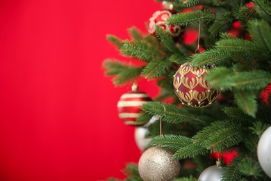 Photo of Beautifully decorated Christmas tree against color background, closeup