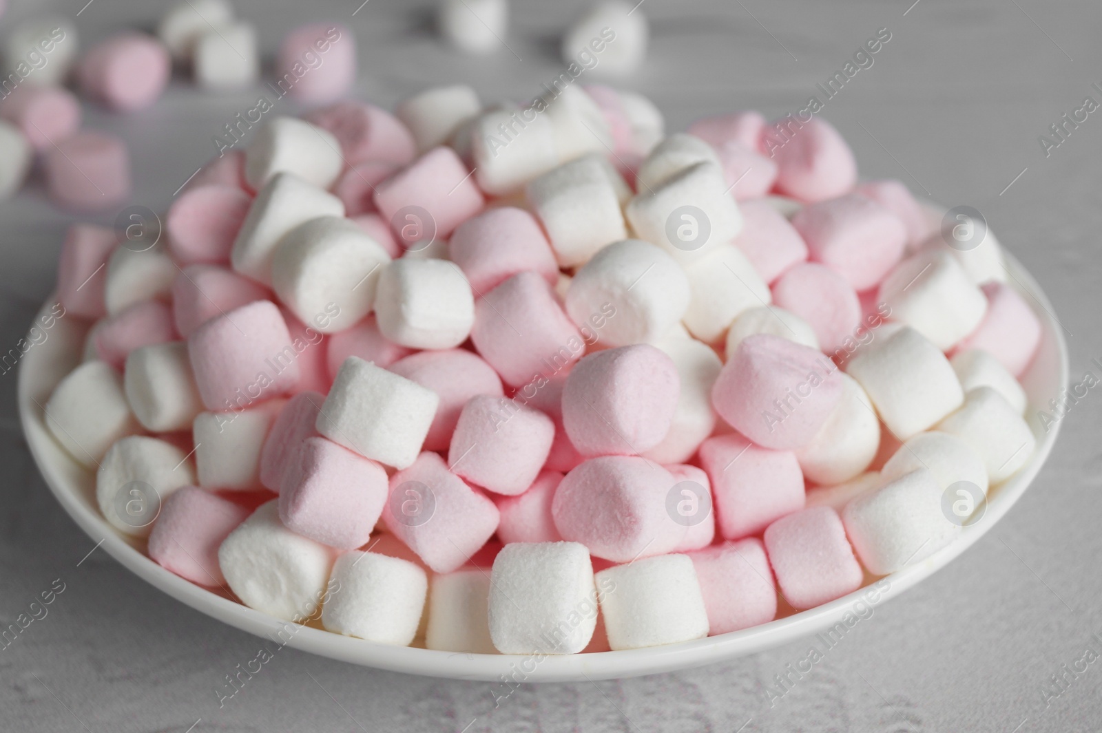 Photo of Plate with delicious marshmallows on light table, closeup