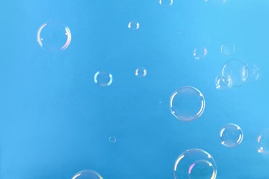 Photo of Beautiful transparent soap bubbles on light blue background