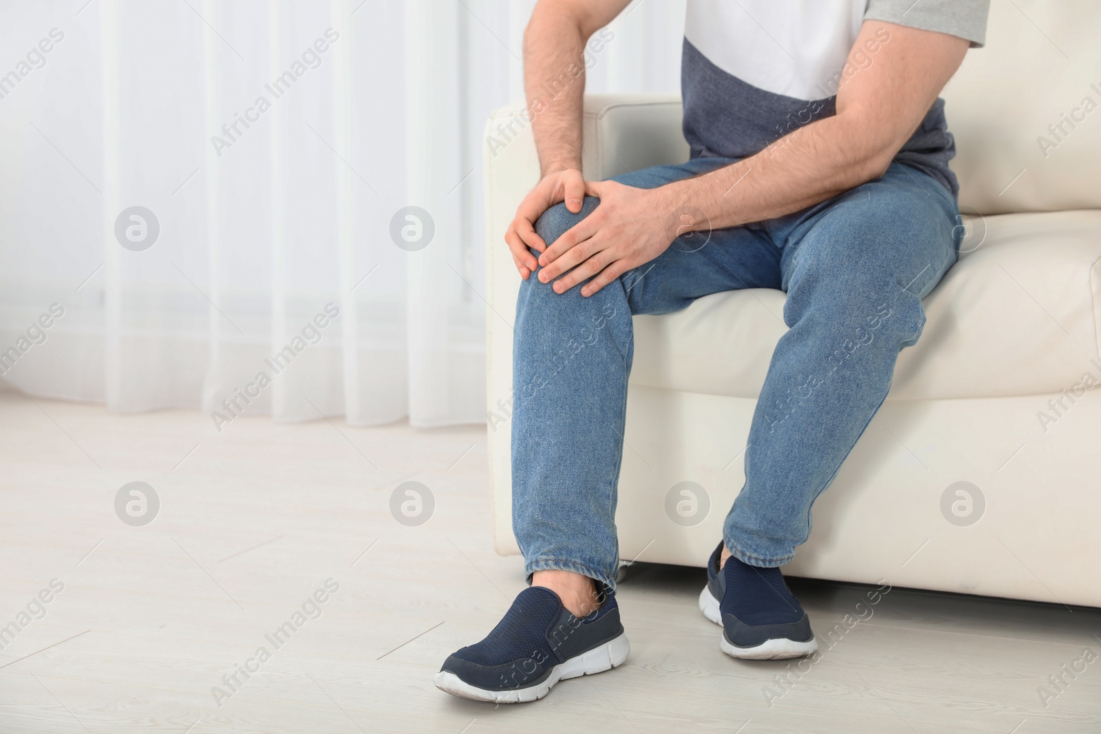 Photo of Young man suffering from leg pain indoors, closeup. Space for text