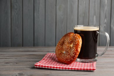 Photo of Tasty pretzel and glass of beer on wooden table, space for text