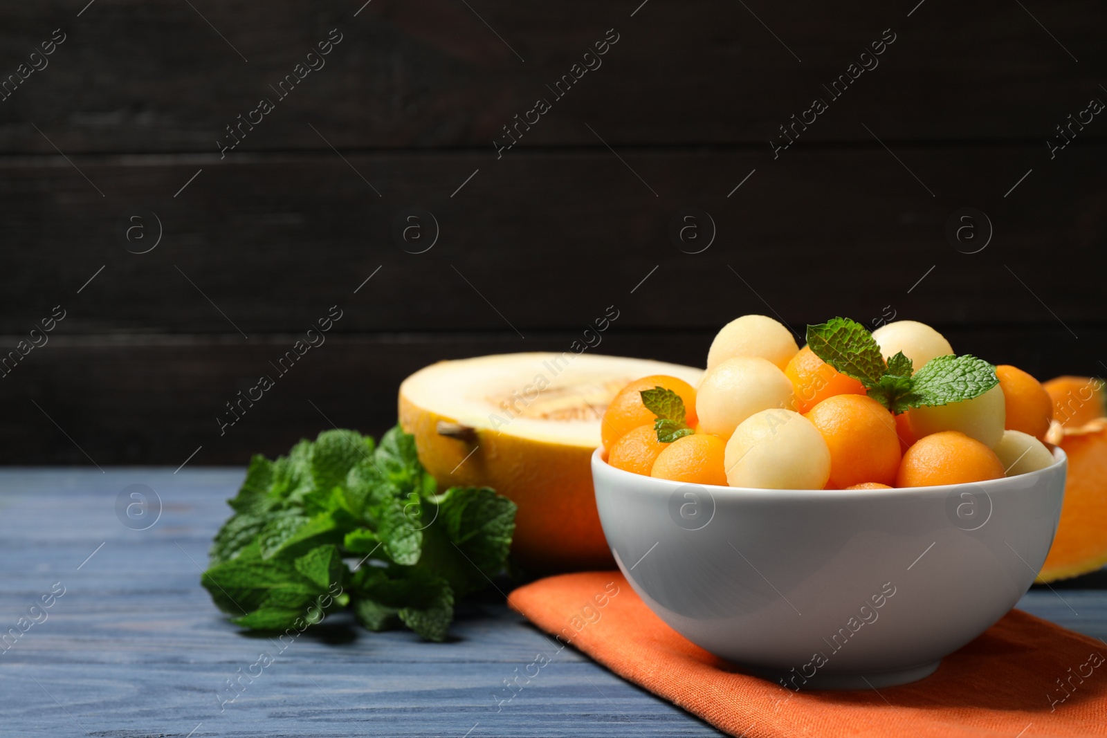 Photo of Melon balls and mint in bowl on blue wooden table