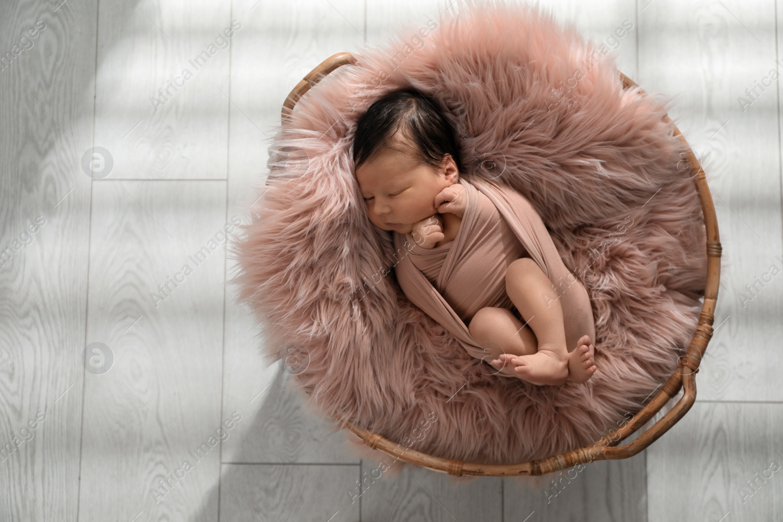 Photo of Cute newborn baby sleeping in wicker basket, top view