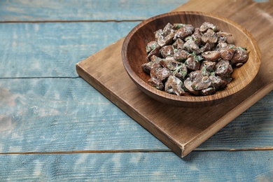 Photo of Bowl of fried mushrooms with sauce on wooden table. Space for text
